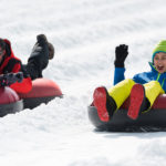 Two kids sledding in snow